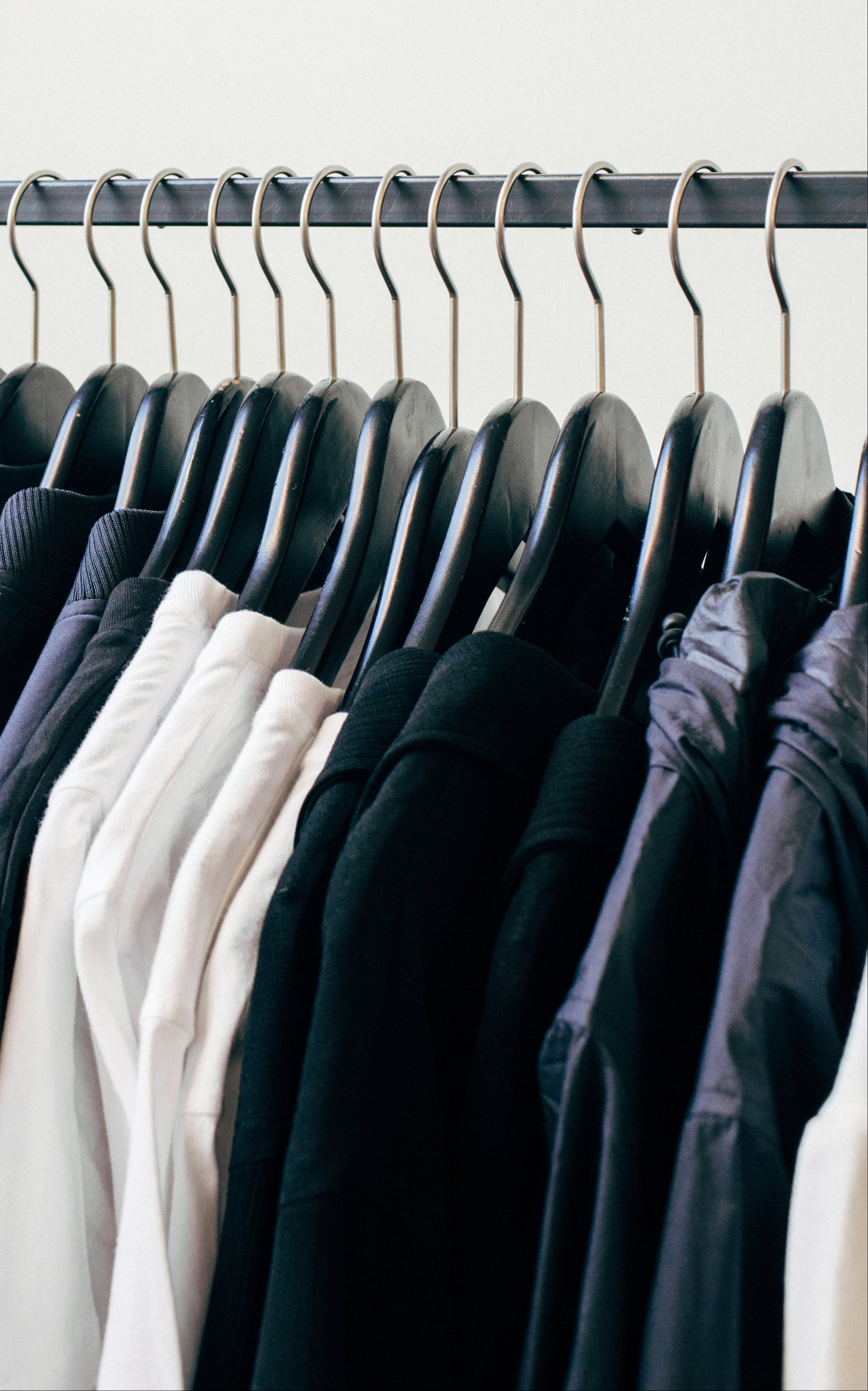Clothing rack with dark-colored shirts against a plain background